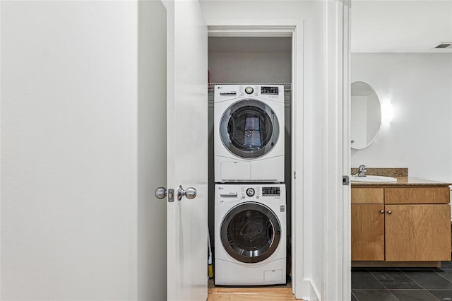 clothes washing area with stacked washer and dryer and sink