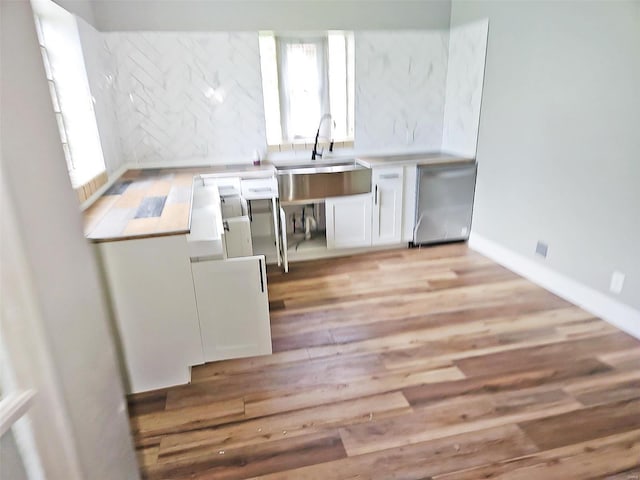 kitchen with white cabinets, light wood-type flooring, dishwashing machine, and a healthy amount of sunlight