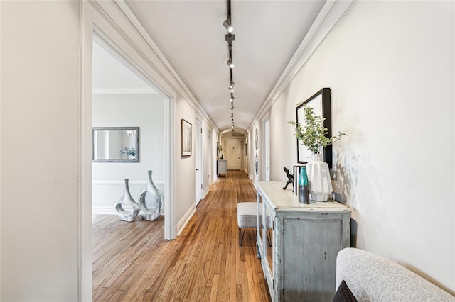 hallway with ornamental molding, track lighting, and light hardwood / wood-style floors