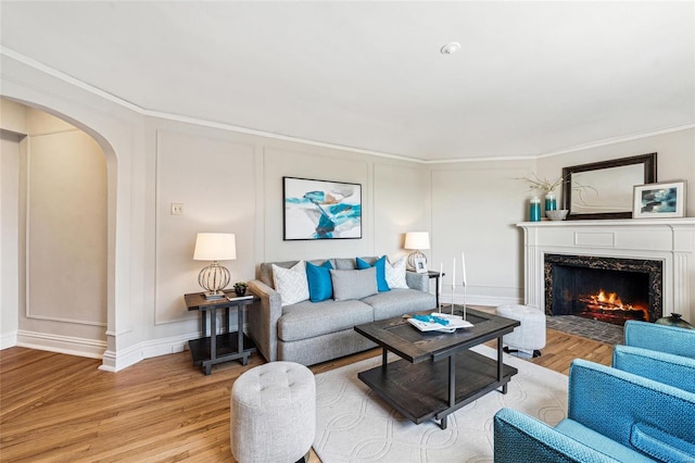 living room featuring ornamental molding, a fireplace, and light wood-type flooring