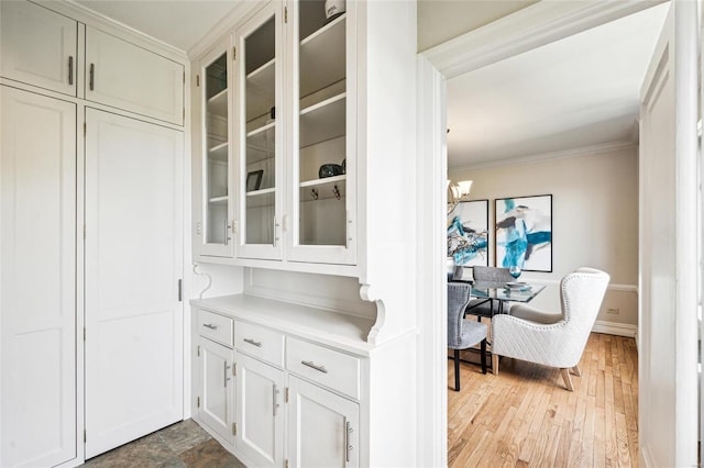 interior space featuring ornamental molding, wood-type flooring, and a notable chandelier