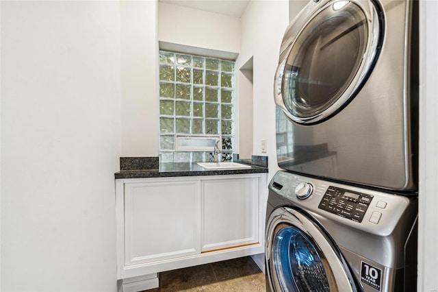 clothes washing area with stacked washer and dryer, cabinets, and sink