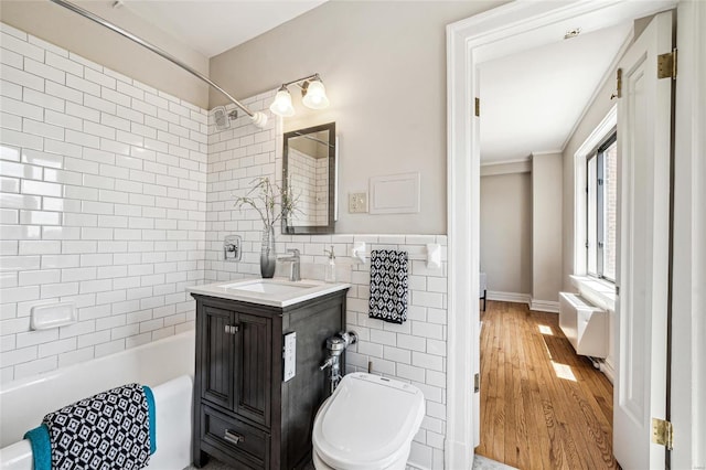 full bathroom with tile walls, tiled shower / bath combo, vanity, hardwood / wood-style flooring, and toilet