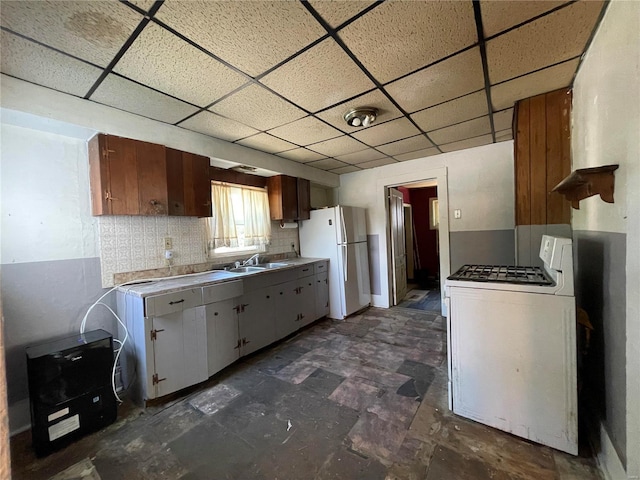 kitchen with sink, a drop ceiling, white appliances, washer / dryer, and decorative backsplash