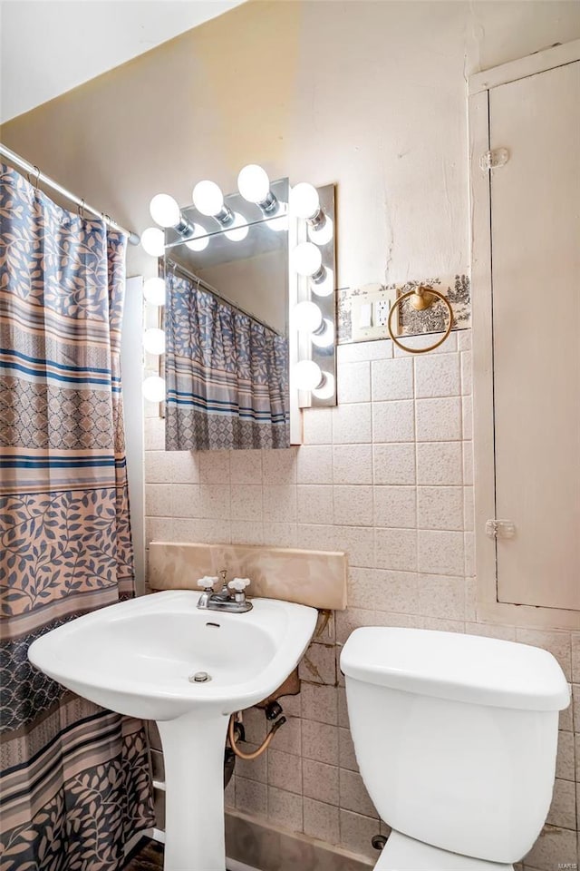 bathroom featuring tasteful backsplash, tile walls, and toilet