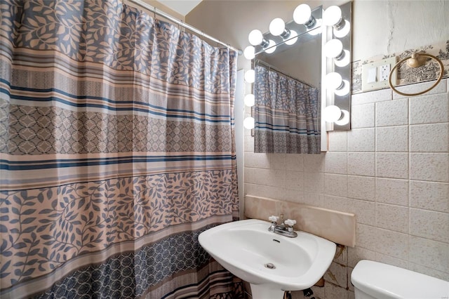 bathroom featuring sink, tile walls, and toilet