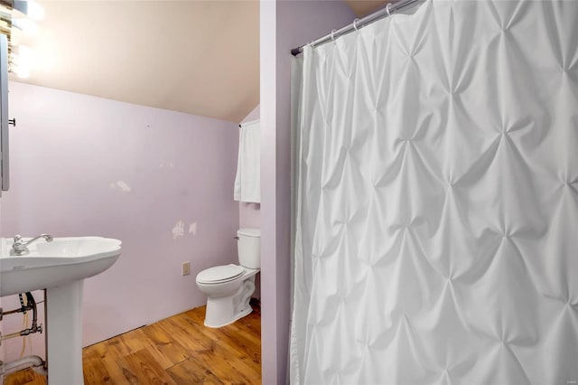 bathroom with curtained shower, sink, lofted ceiling, toilet, and hardwood / wood-style flooring