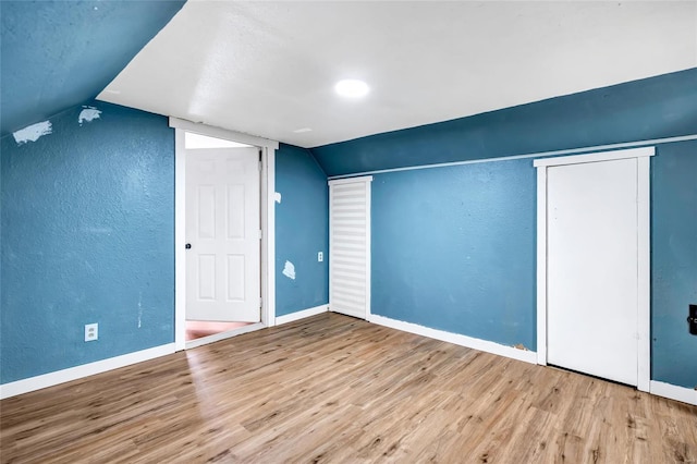 additional living space with light wood-type flooring and lofted ceiling