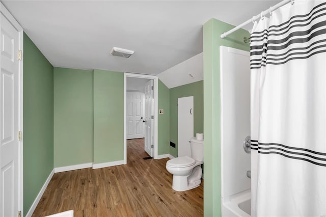 bathroom with wood-type flooring, vaulted ceiling, shower / tub combo, and toilet