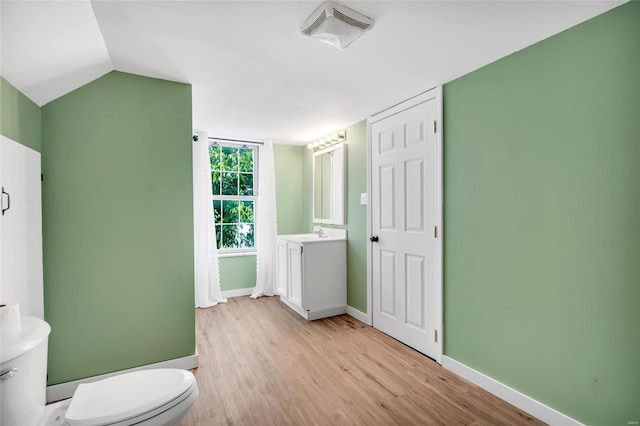 bathroom with vanity, wood-type flooring, vaulted ceiling, and toilet