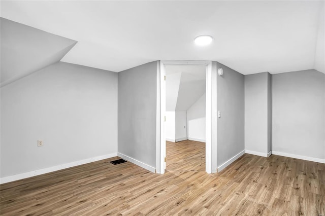 additional living space with light hardwood / wood-style flooring and lofted ceiling