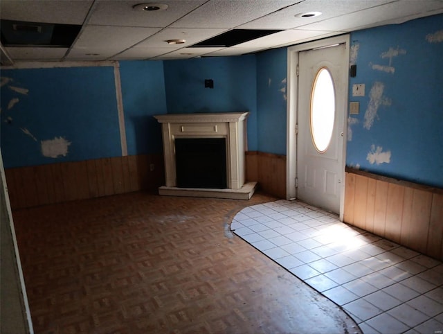 entryway with wood walls, a paneled ceiling, and light tile patterned flooring