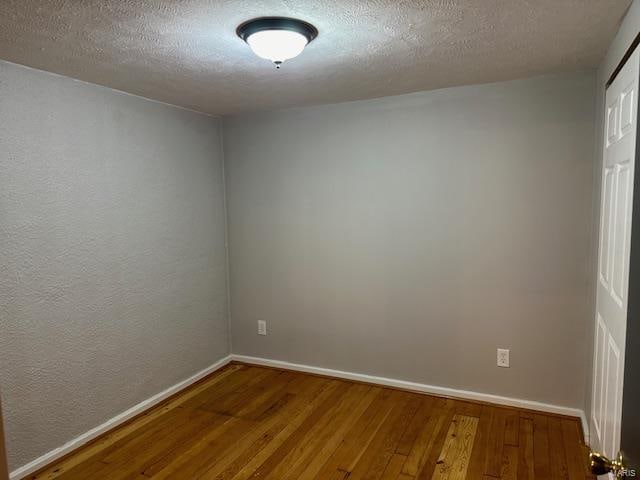 empty room with wood-type flooring and a textured ceiling