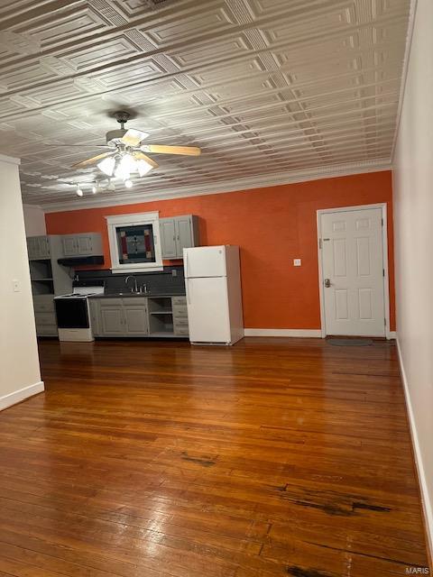 unfurnished living room with ceiling fan, sink, crown molding, and dark hardwood / wood-style floors