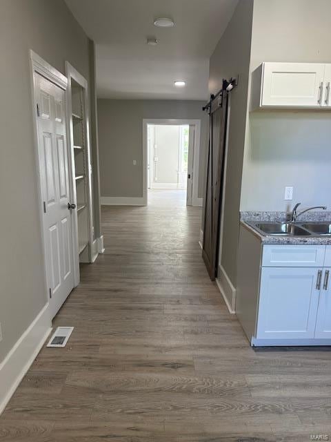 corridor featuring a barn door, sink, and light hardwood / wood-style flooring