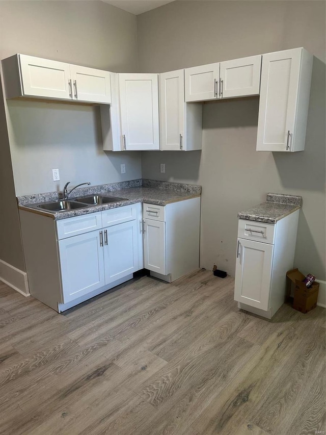 kitchen featuring white cabinets, light hardwood / wood-style floors, and sink