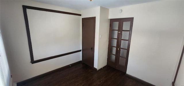 empty room with dark hardwood / wood-style flooring and french doors