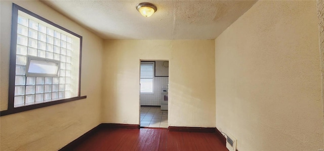 empty room with a textured ceiling and dark hardwood / wood-style floors