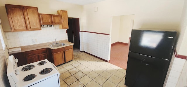 kitchen featuring black fridge, sink, electric range, and light hardwood / wood-style floors