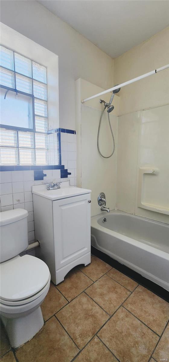 full bathroom featuring tile patterned floors, toilet, shower / washtub combination, vanity, and tile walls