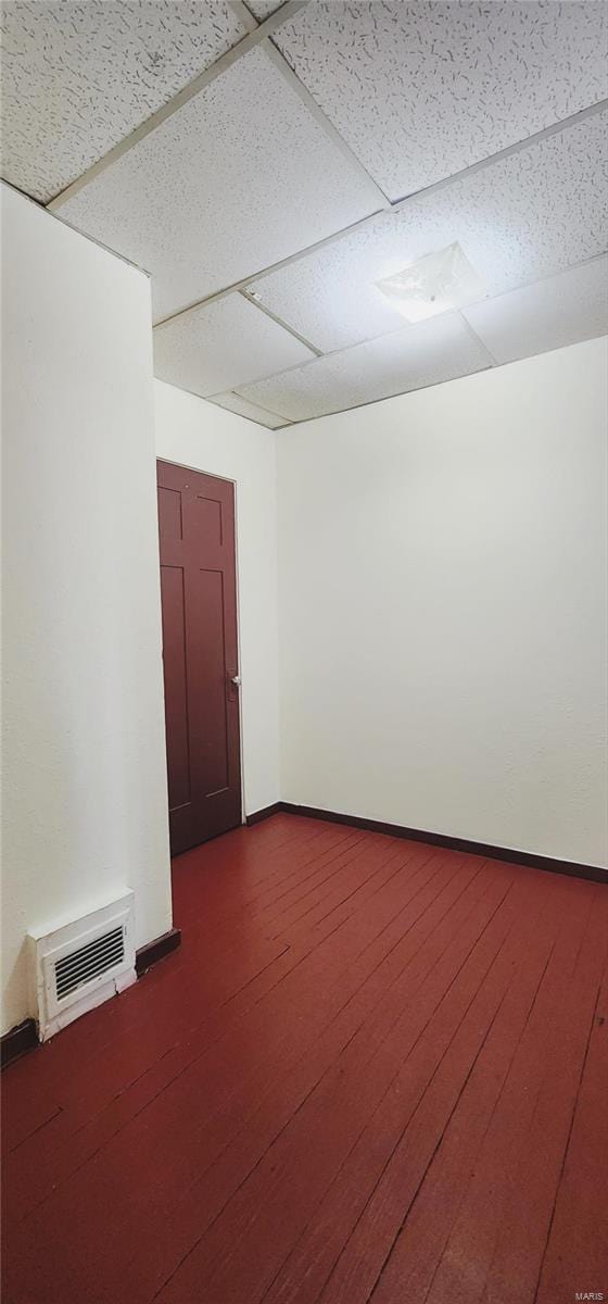 empty room featuring a paneled ceiling and hardwood / wood-style flooring