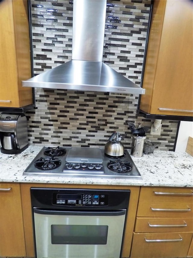 kitchen with backsplash, wall chimney exhaust hood, and appliances with stainless steel finishes