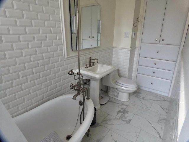 bathroom featuring a bathing tub, toilet, and tile walls