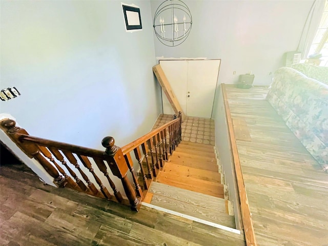 stairway featuring hardwood / wood-style floors and an inviting chandelier