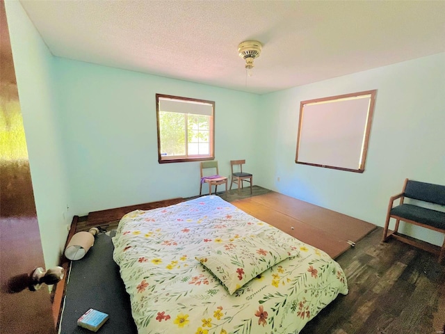 bedroom with dark hardwood / wood-style floors and a textured ceiling