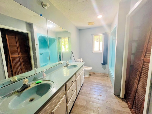 bathroom featuring vanity, toilet, a textured ceiling, walk in shower, and wood-type flooring