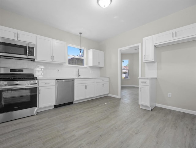 kitchen featuring white cabinets, decorative light fixtures, and appliances with stainless steel finishes