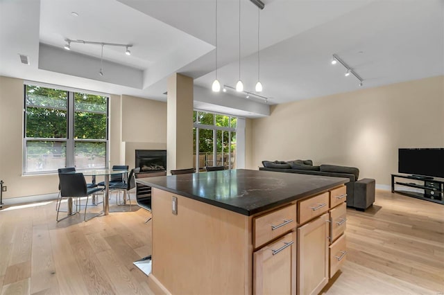 kitchen featuring decorative light fixtures, light brown cabinetry, light hardwood / wood-style floors, and a kitchen island