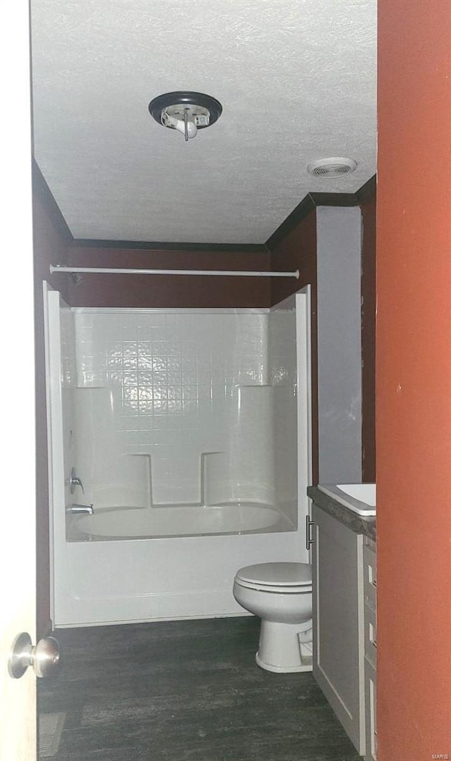 full bathroom with hardwood / wood-style floors, vanity, washtub / shower combination, toilet, and a textured ceiling