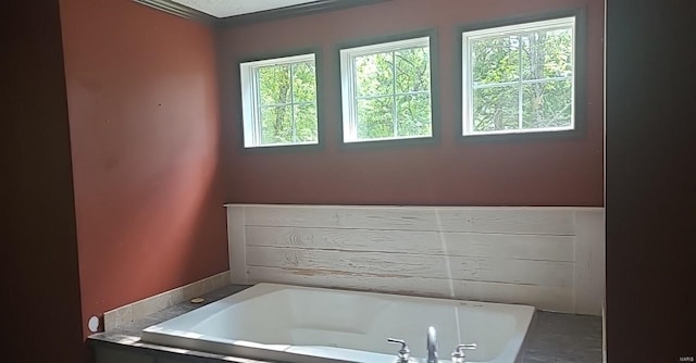 bathroom featuring a wealth of natural light and tiled tub