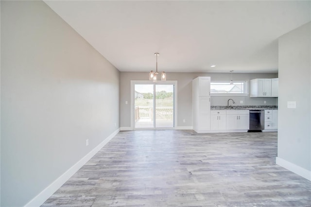 unfurnished living room featuring an inviting chandelier, sink, and light hardwood / wood-style floors