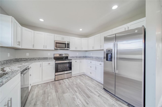 kitchen with white cabinets, light stone countertops, light hardwood / wood-style flooring, and appliances with stainless steel finishes