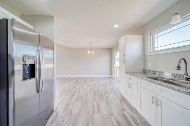 kitchen with light hardwood / wood-style flooring, sink, light stone countertops, stainless steel fridge with ice dispenser, and white cabinetry