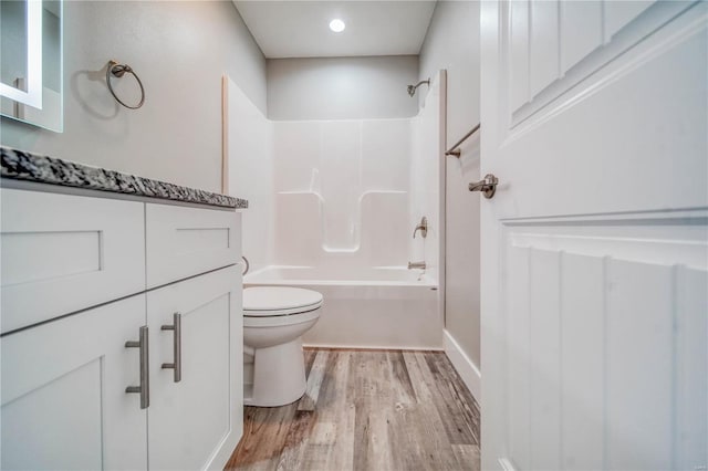 full bathroom with washtub / shower combination, wood-type flooring, toilet, and vanity