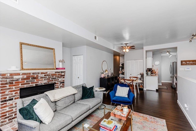 living room featuring dark hardwood / wood-style floors, ceiling fan, and a fireplace