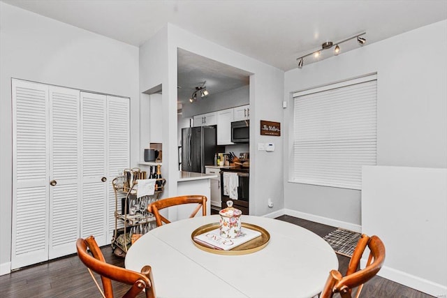 dining room with dark hardwood / wood-style floors and rail lighting