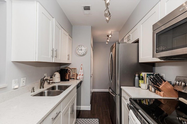 kitchen featuring dark wood-type flooring, stainless steel appliances, white cabinets, sink, and track lighting