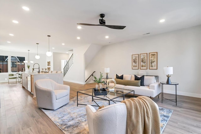 living room featuring ceiling fan, light hardwood / wood-style floors, and sink