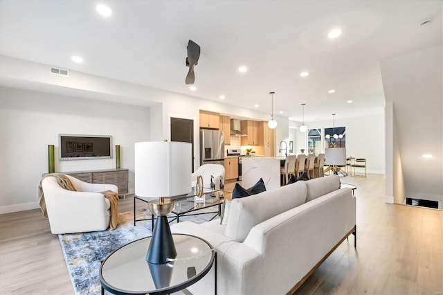 living room with light hardwood / wood-style floors, ceiling fan, and sink