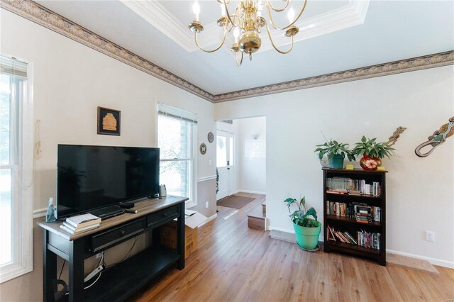 living room featuring crown molding, a raised ceiling, an inviting chandelier, and hardwood / wood-style floors