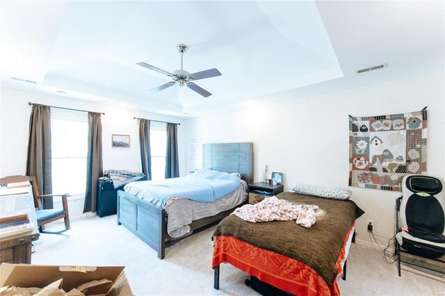 bedroom featuring a tray ceiling, carpet, and ceiling fan