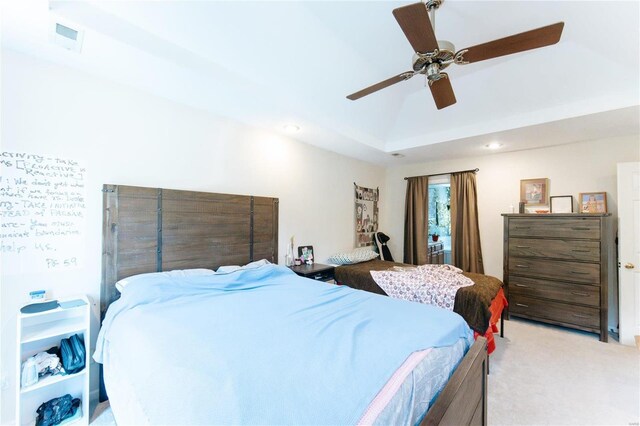 carpeted bedroom with ceiling fan and a tray ceiling