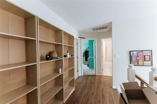 hallway with wood-type flooring and built in features