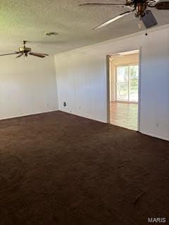 spare room with ceiling fan and dark carpet