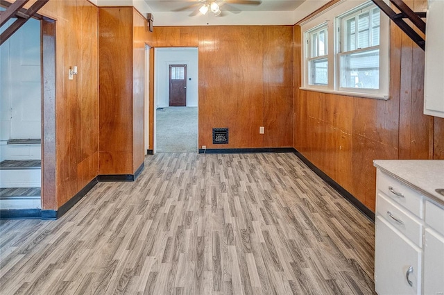 spare room featuring ceiling fan, wood walls, and light wood-type flooring