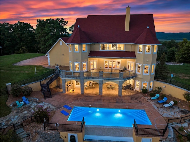 pool at dusk featuring a yard and a patio